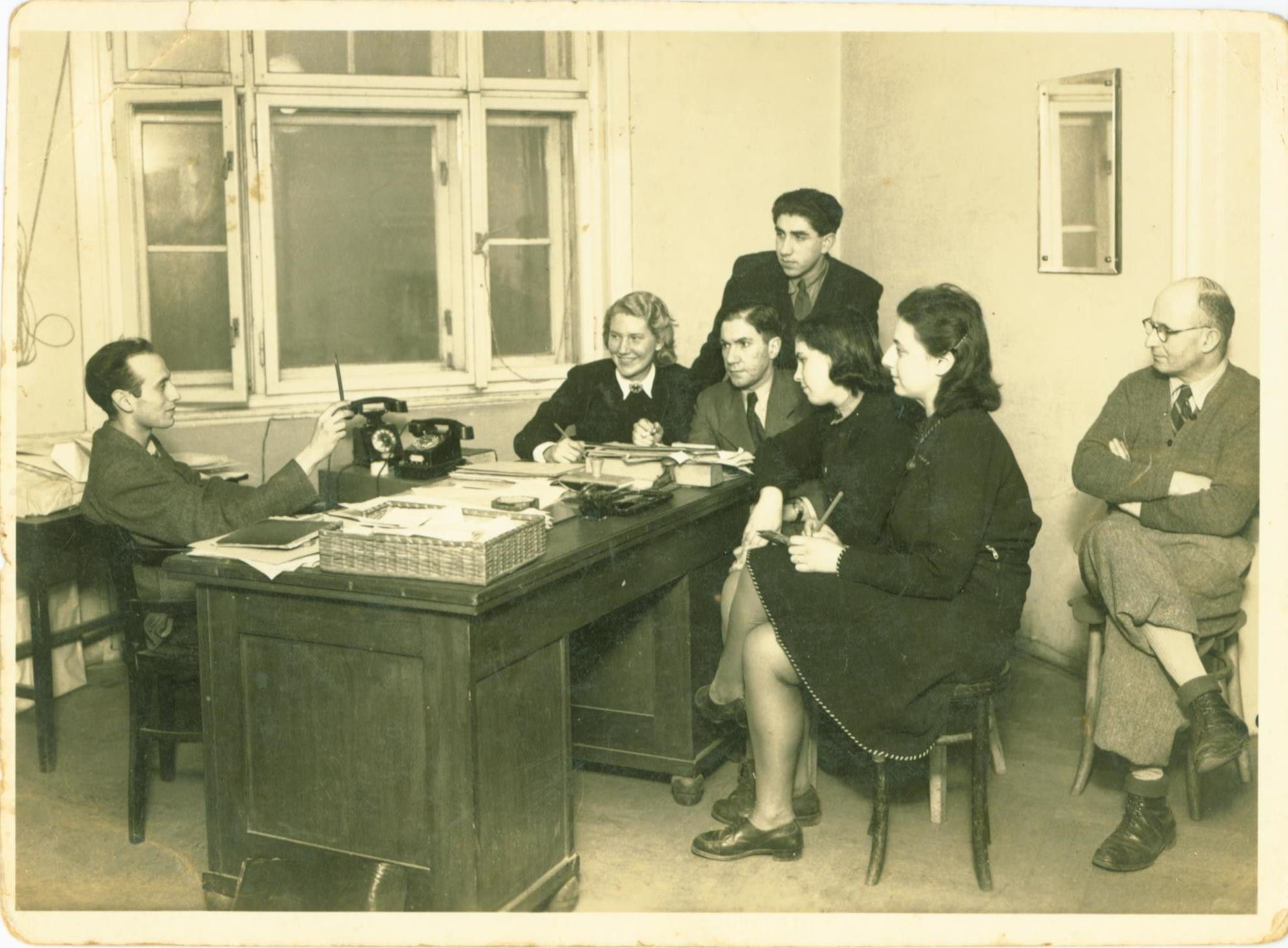 Pracovníci Dokumentační akce v Praze, 1946. Zleva: Zeev Schek, Edita Saxlová, Robert Weinberger, Harald Tressler (stojící), Berta Gerzonová, Ruth Bondy, Jiří Lauscher. Fotografie byla uveřejněna se svolením Rachel Shek.